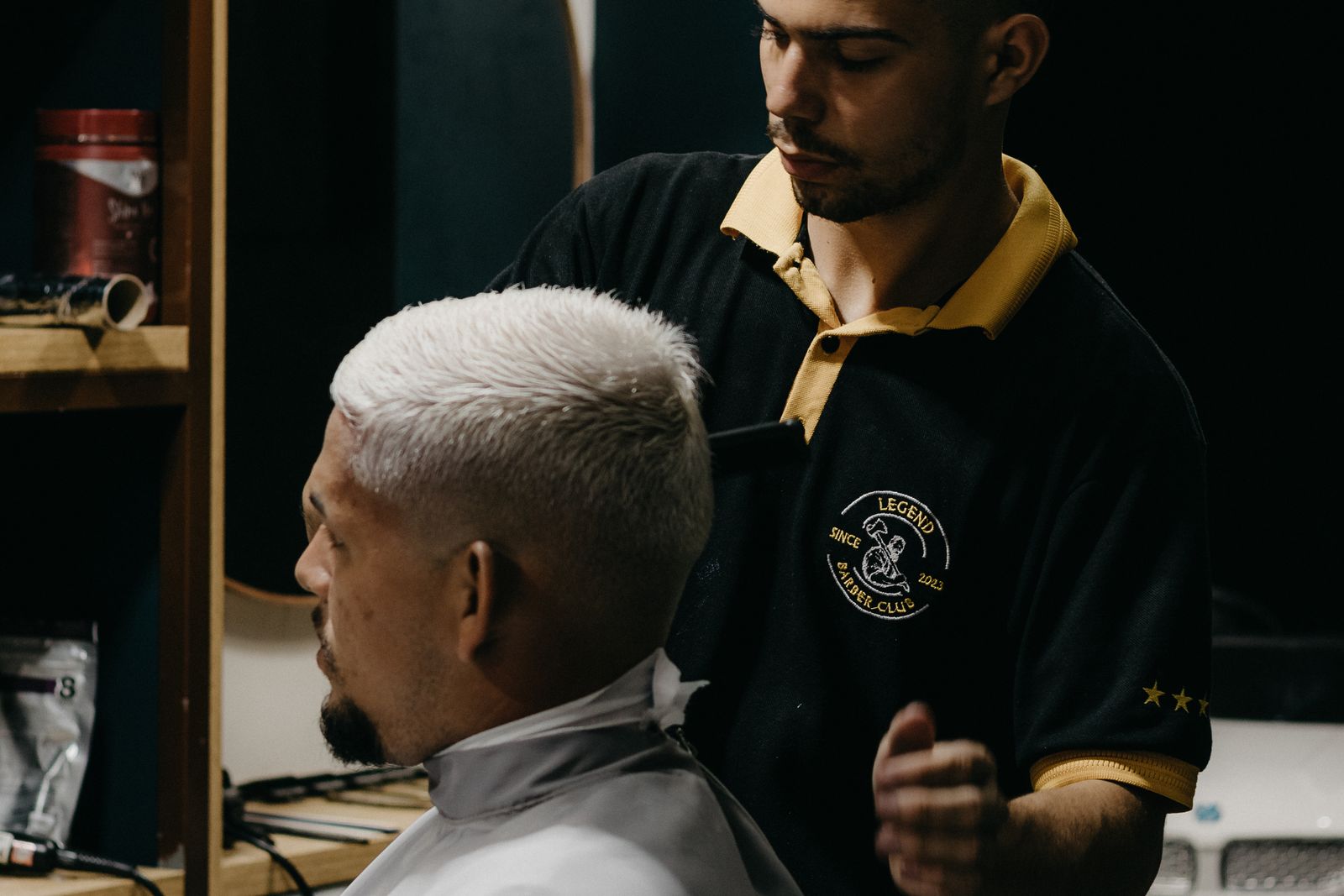 A barber works on a client's cut in the shop.