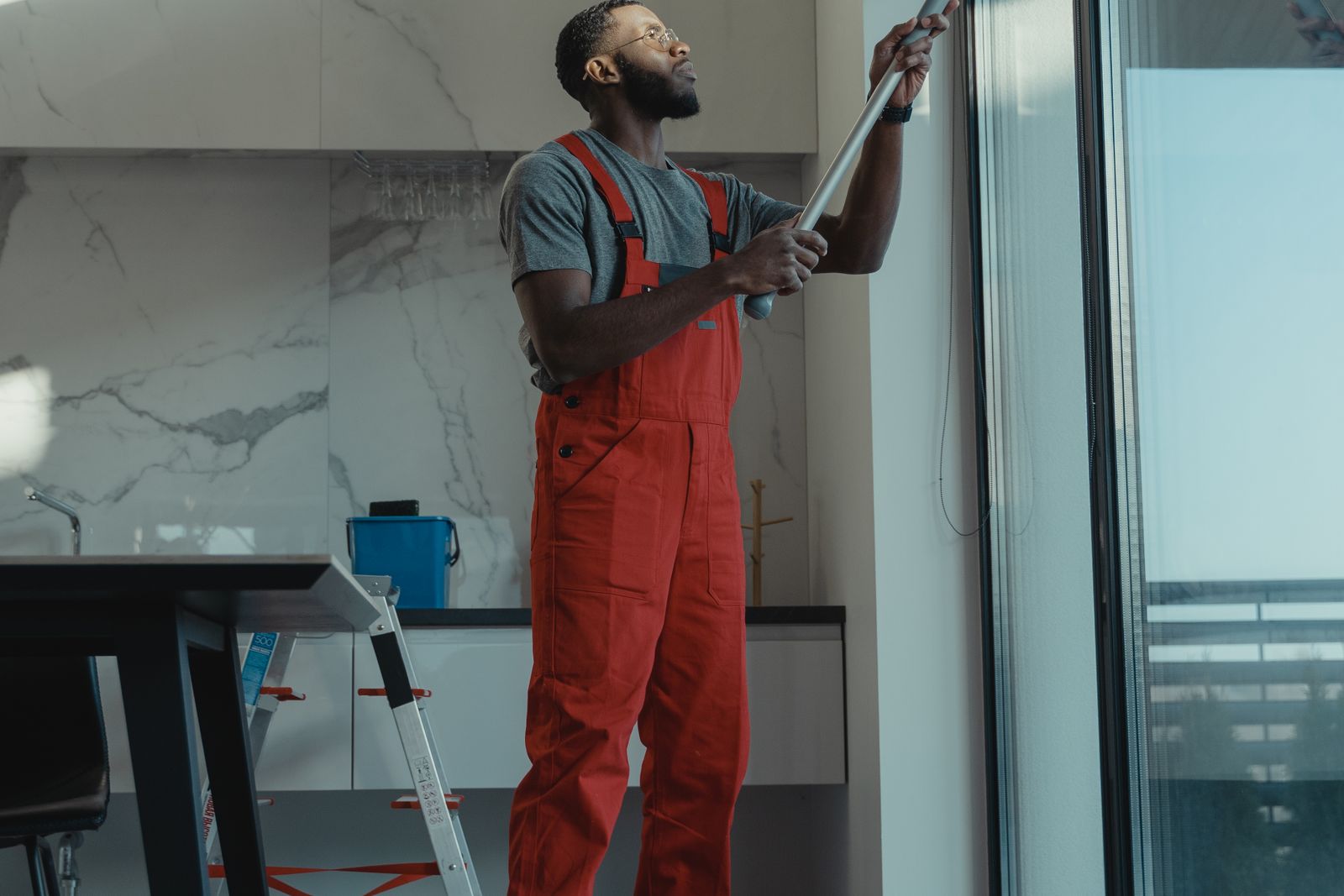 A cleaner in coveralls squeegees a floor-to-ceiling window.
