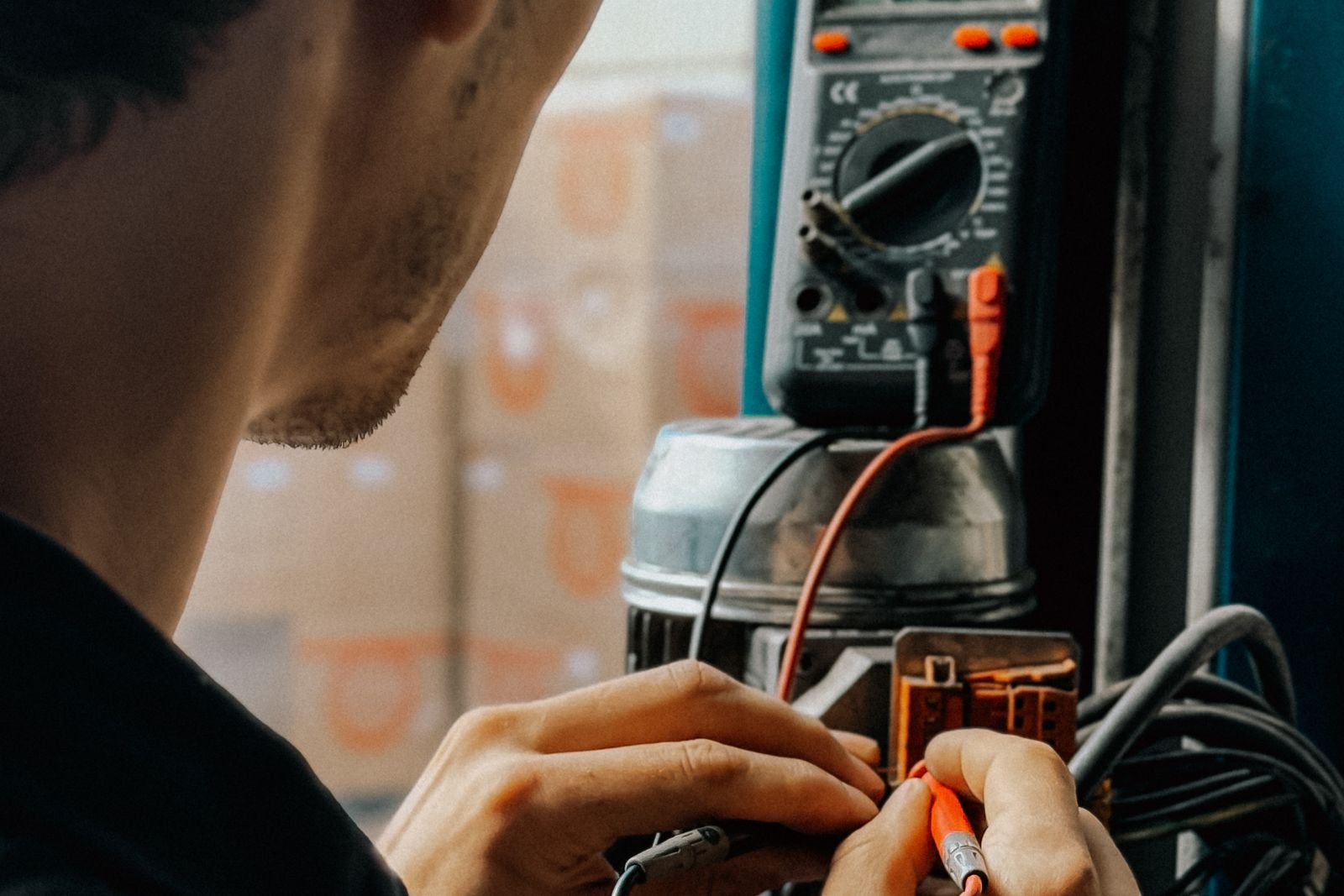 An electrician tests a panel with a multimeter.