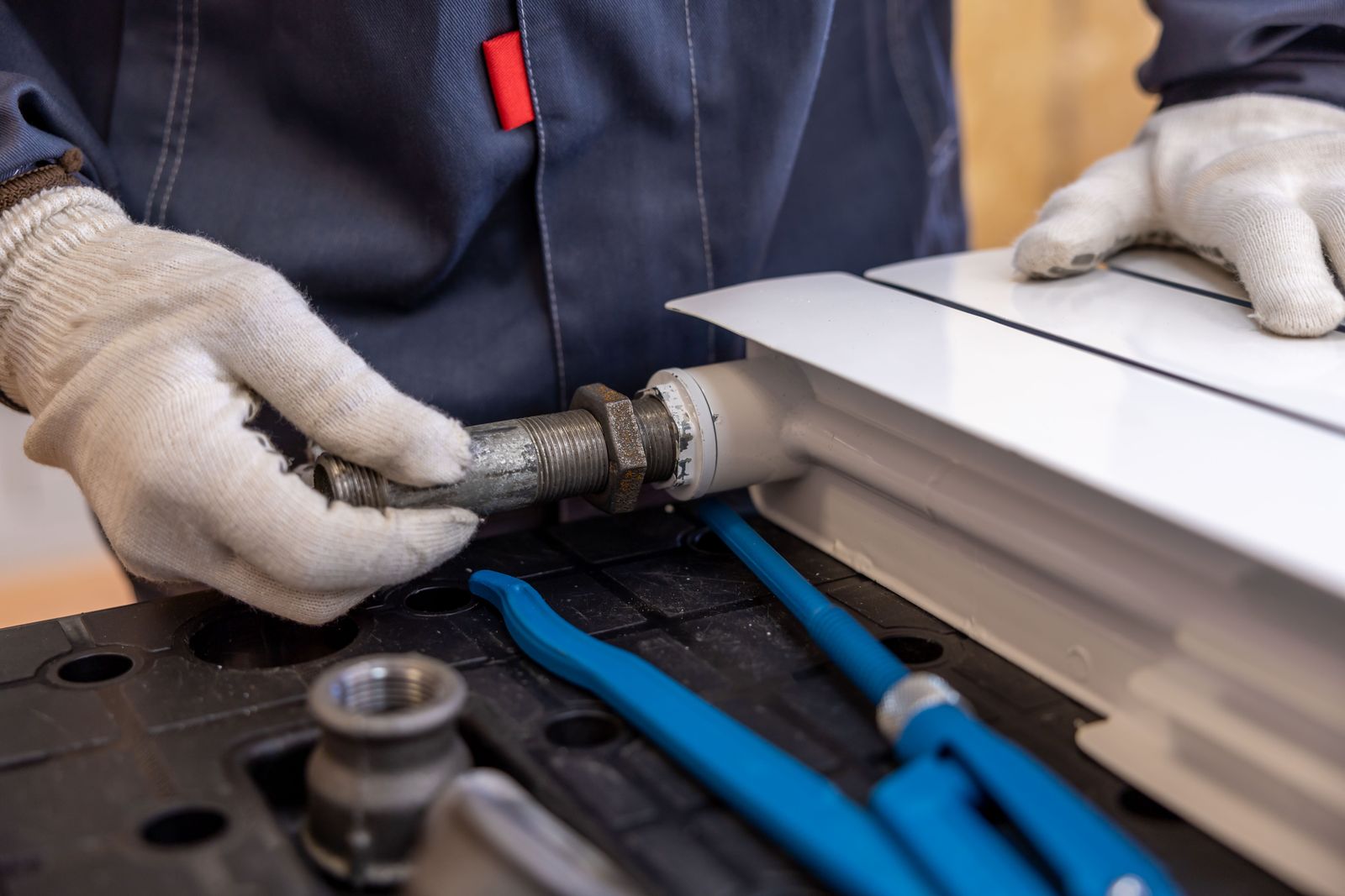 A plumber fits a valve to a radiator pipe.