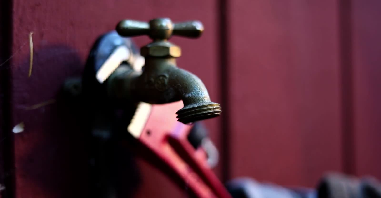 A still from the Copperline Plumbing concept build's video hero: a brass outdoor faucet beside a red pipe wrench.